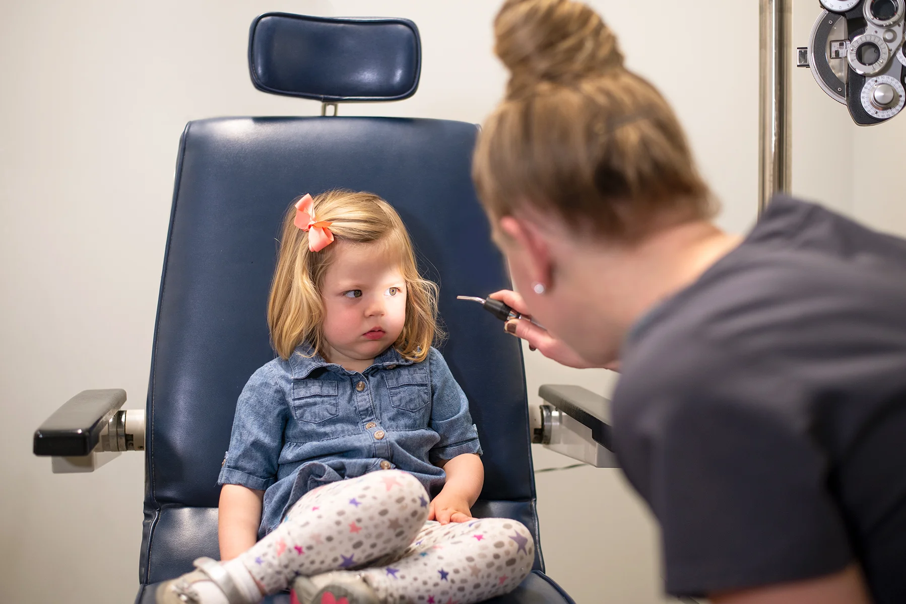 Optometric assistant shining a light into the eye of a child